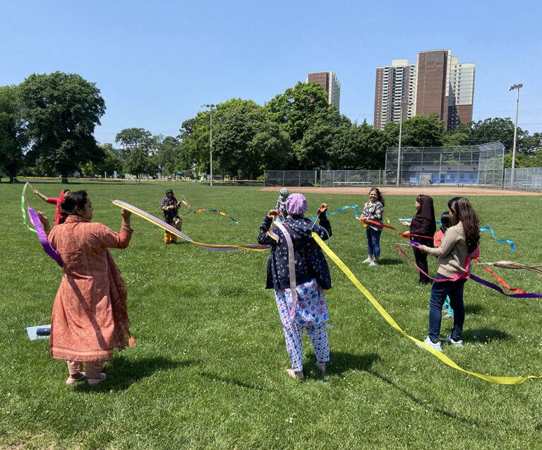 Bengali speaking participants, in Dentonia Park, engaging in a dance ribbon activity to learn about somatic resourcing for self-regulation.